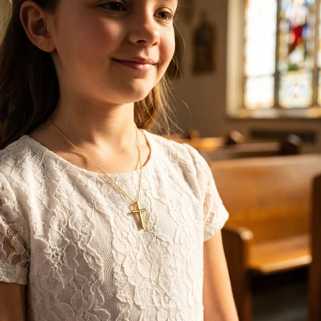 A girl wearing the Milestone Cross for her First Communion